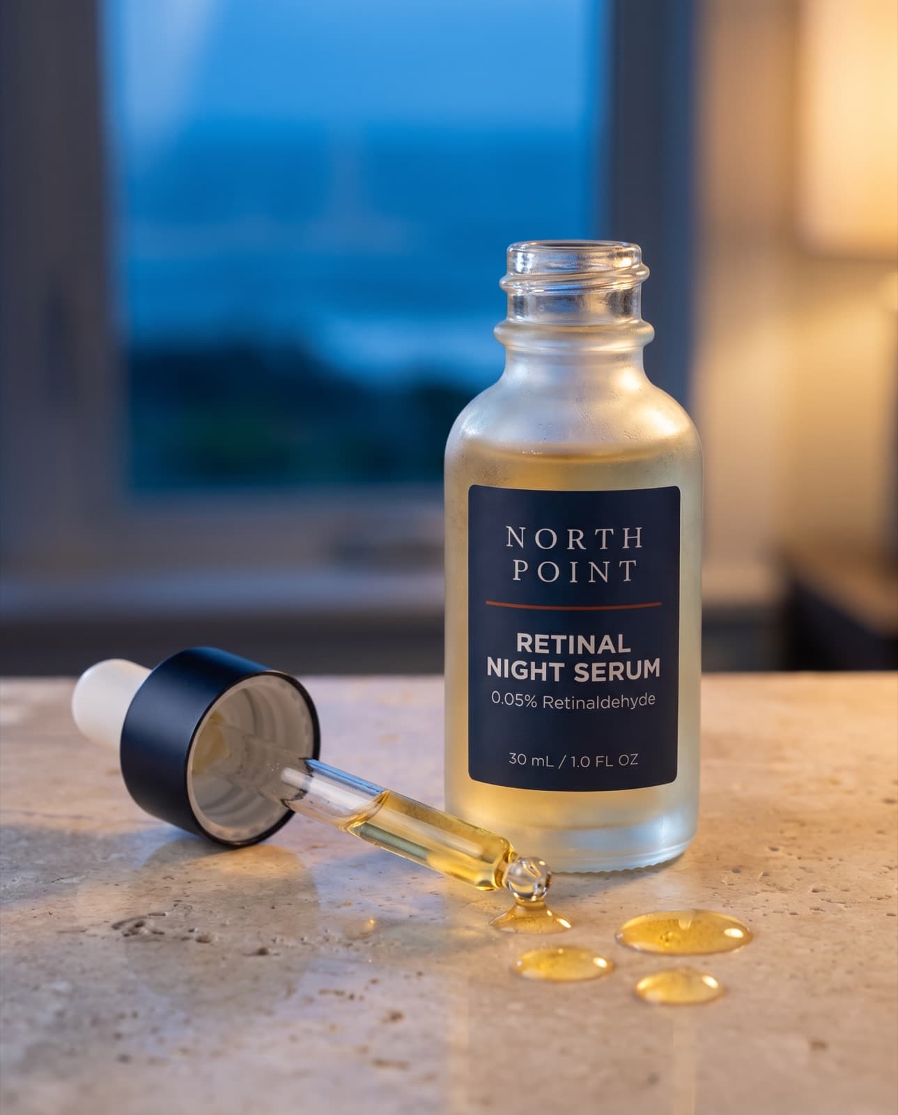 Retinal Night Serum with its dropper and three drops of serum on a limestone counter at dusk